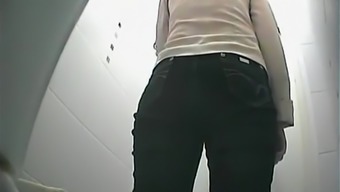Girl in black jeans pants pissing in toilet