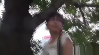 Nerdy Asian cocktease kneels for pissing behind tree